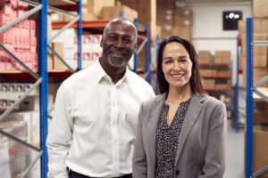 Logistics professionals smiling in a warehouse, emphasizing the impact of effective sales outreach tools for logistics companies.